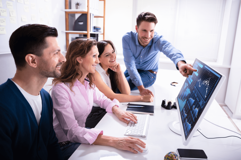 Deze afbeelding toont een team van collega’s dat samen naar gegevens op een computerscherm kijkt.
