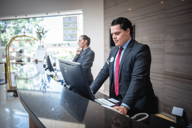Foto van man en vrouw achter de receptie, ze hebben een klantgerichte houding