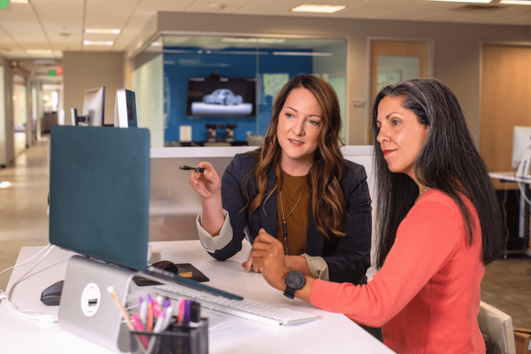 Foto van twee vrouwen die iets bespreken achter een laptop