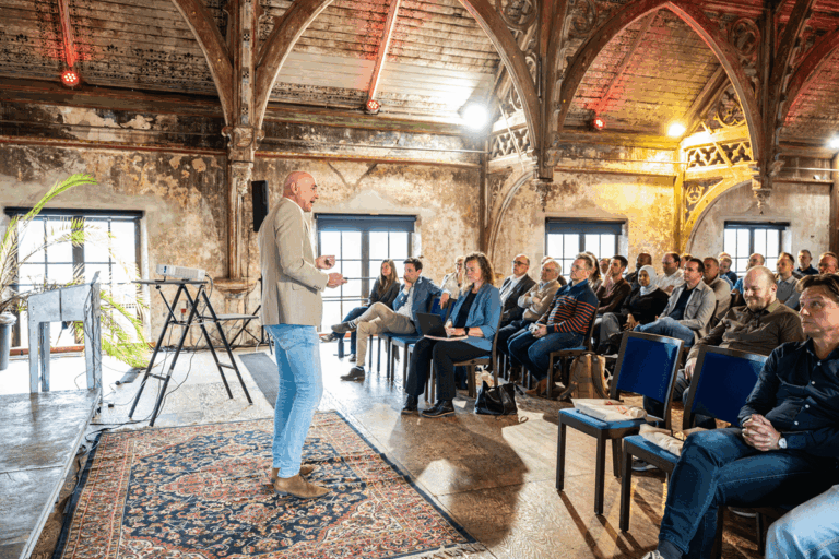 Daan van Beek geeft een masterclass over data en AI aan een betrokken publiek in een rustieke ruimte.