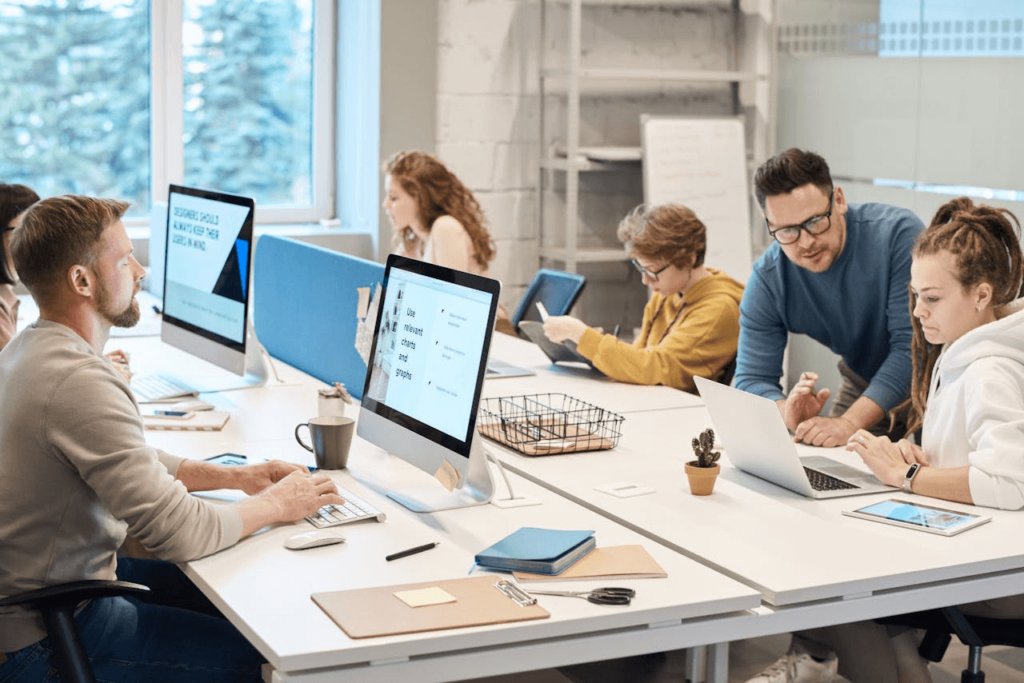 Professionals die samenwerken in een kantoor met laptops, tablets en beeldschermen.